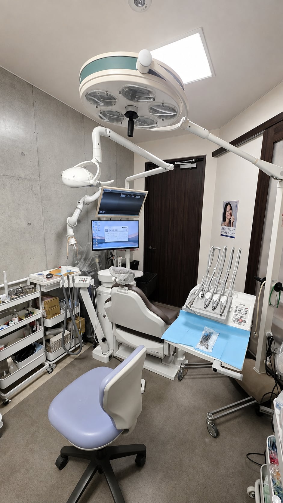 診療チェア、モニター、天井の照明を備えた当院の個室診療室